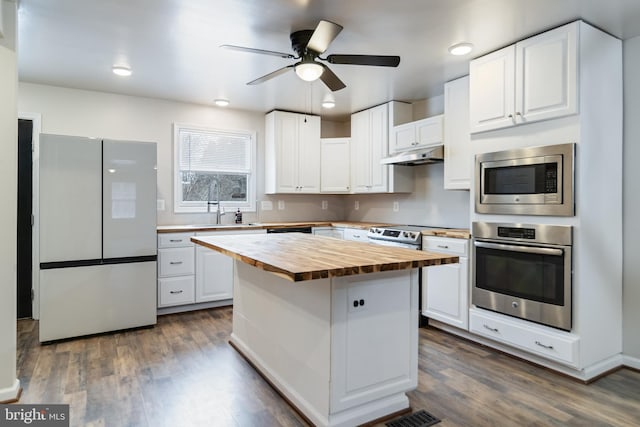 kitchen with white cabinetry, butcher block countertops, stainless steel appliances, and a center island