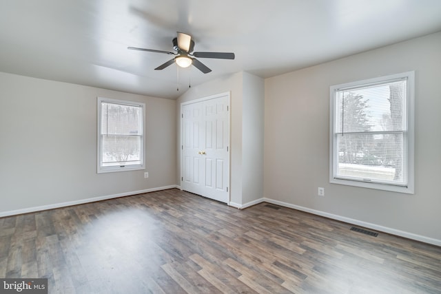 unfurnished bedroom featuring lofted ceiling, a closet, dark hardwood / wood-style floors, and ceiling fan