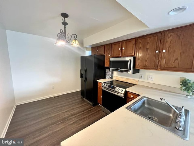 kitchen with sink, hanging light fixtures, a notable chandelier, stainless steel appliances, and dark wood-type flooring