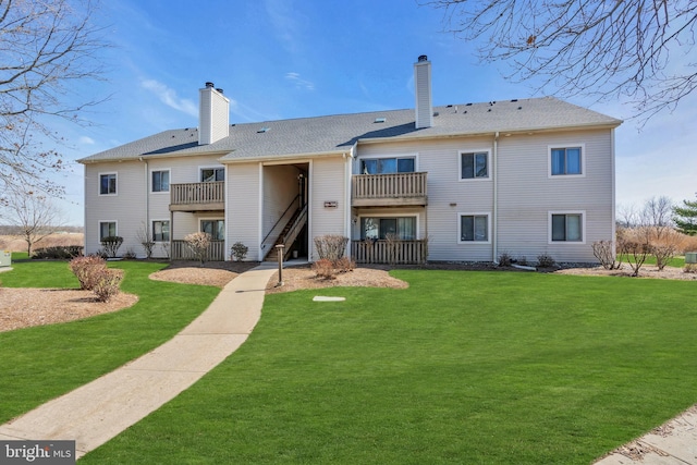 rear view of property featuring a balcony and a yard