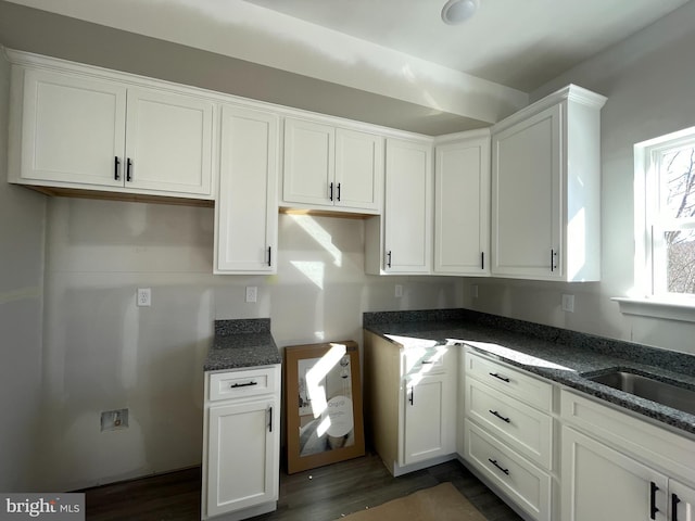 kitchen with white cabinets, a sink, and dark stone countertops