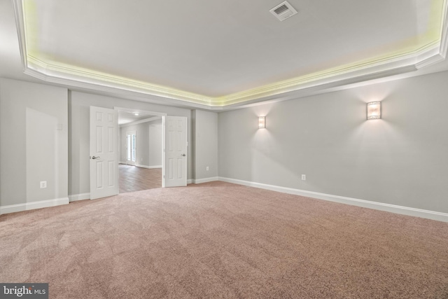 carpeted spare room featuring ornamental molding and a tray ceiling