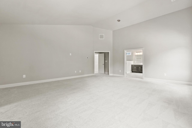 unfurnished living room featuring high vaulted ceiling and light carpet