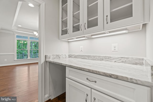 bar featuring crown molding, dark hardwood / wood-style flooring, white cabinets, a tray ceiling, and light stone counters