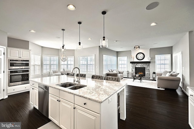 kitchen with white cabinets, sink, pendant lighting, stainless steel appliances, and a center island with sink