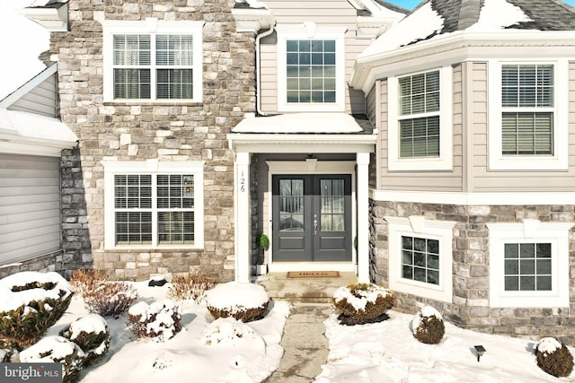 snow covered property entrance featuring french doors