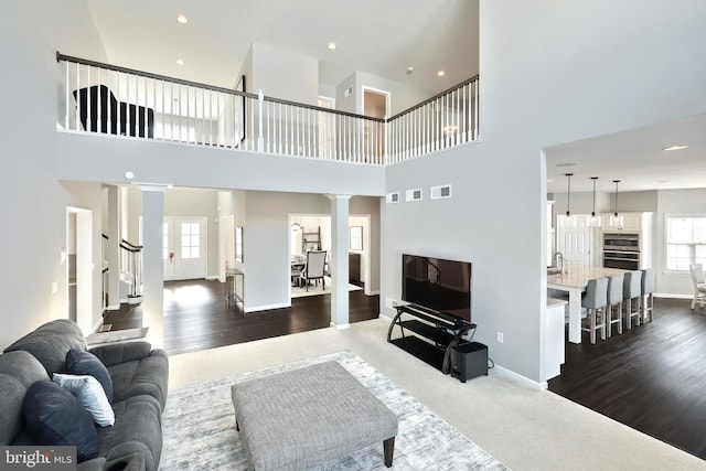 living room featuring decorative columns, a high ceiling, and dark colored carpet