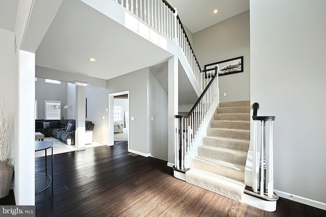 entryway with hardwood / wood-style flooring, ornate columns, and a towering ceiling