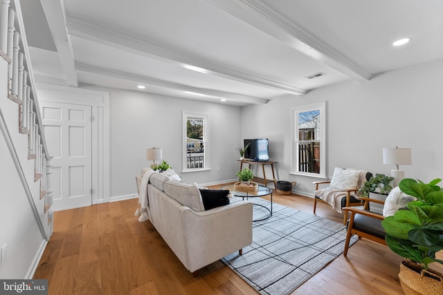 living room with plenty of natural light, light hardwood / wood-style flooring, and beam ceiling