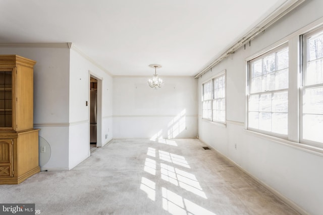 unfurnished dining area featuring ornamental molding, light carpet, and an inviting chandelier