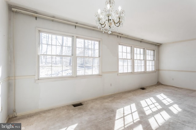 carpeted spare room featuring a notable chandelier