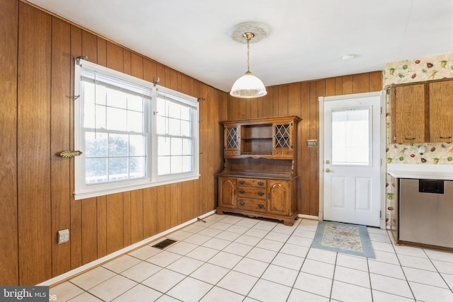 kitchen with plenty of natural light, light tile patterned floors, and wood walls