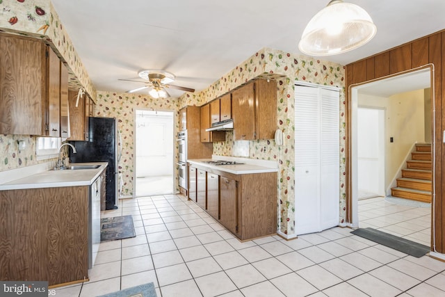 kitchen featuring pendant lighting, sink, light tile patterned floors, ceiling fan, and stainless steel double oven