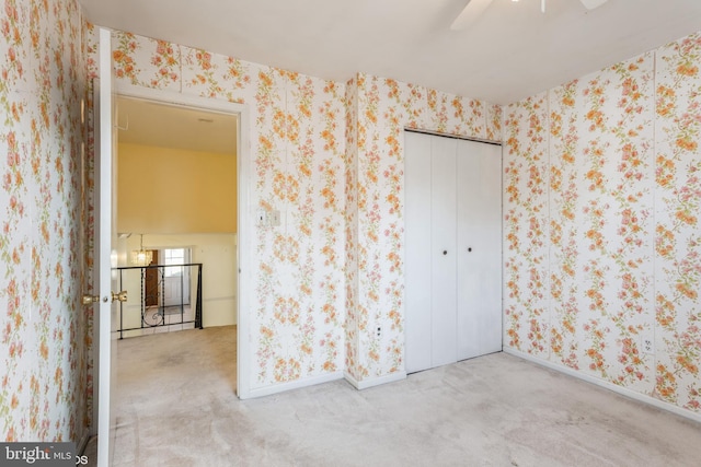 empty room featuring ceiling fan and light colored carpet