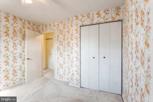 unfurnished bedroom with light carpet, a closet, and ceiling fan