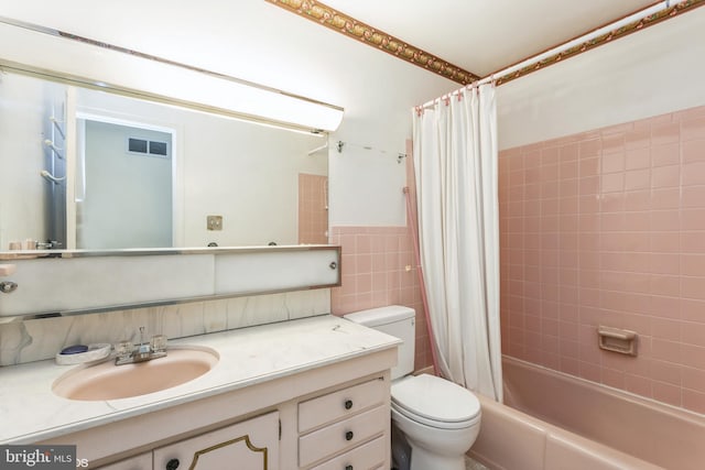 full bathroom featuring tile walls, vanity, toilet, and shower / bath combo