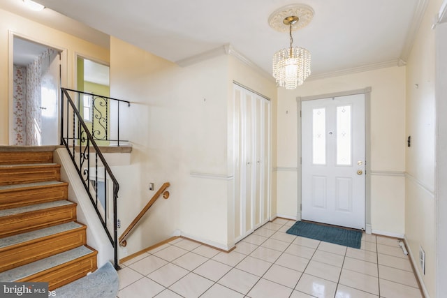 tiled foyer entrance featuring ornamental molding and a chandelier