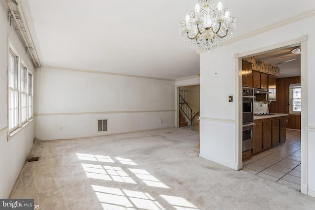 interior space with ornamental molding, light colored carpet, and an inviting chandelier