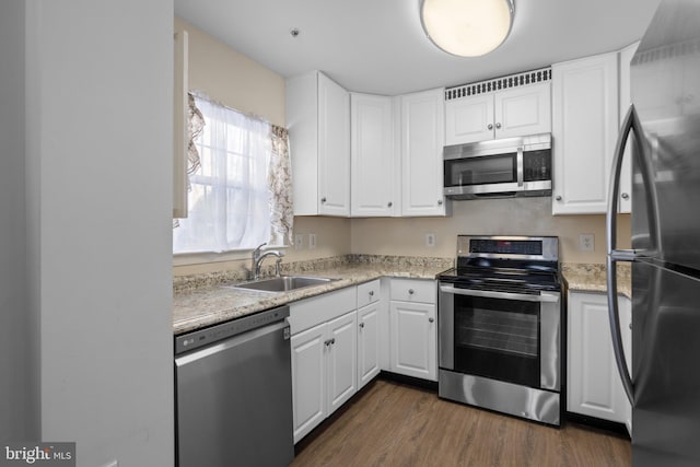 kitchen featuring sink, stainless steel appliances, dark hardwood / wood-style floors, light stone counters, and white cabinets