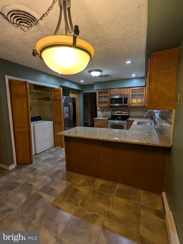 kitchen with washer / clothes dryer, sink, stainless steel appliances, and kitchen peninsula