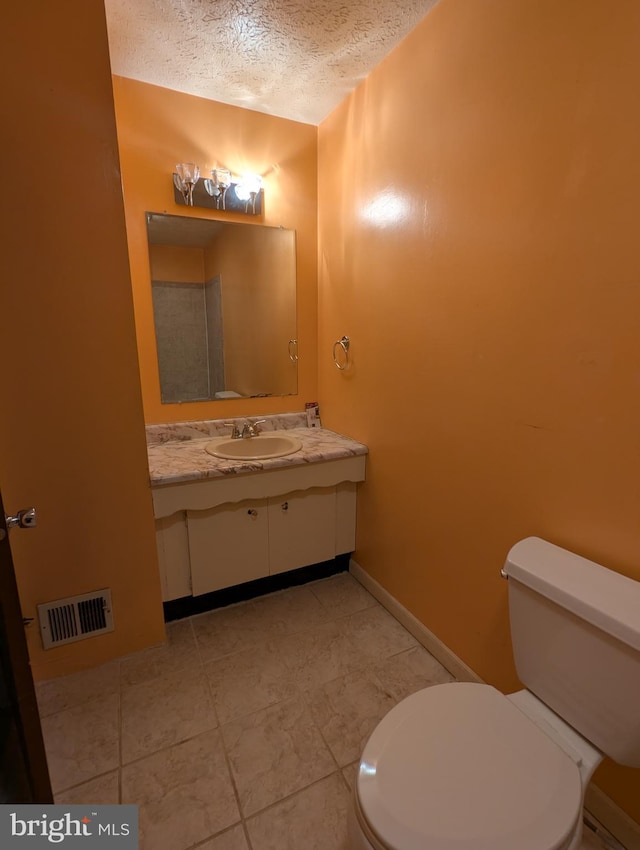 bathroom featuring vanity, toilet, and a textured ceiling