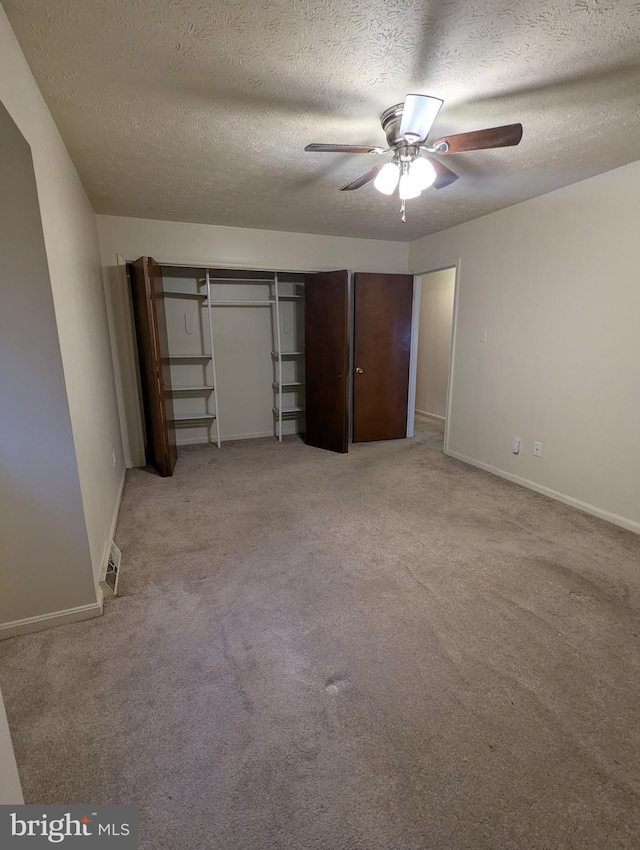 unfurnished bedroom featuring a closet, ceiling fan, light colored carpet, and a textured ceiling