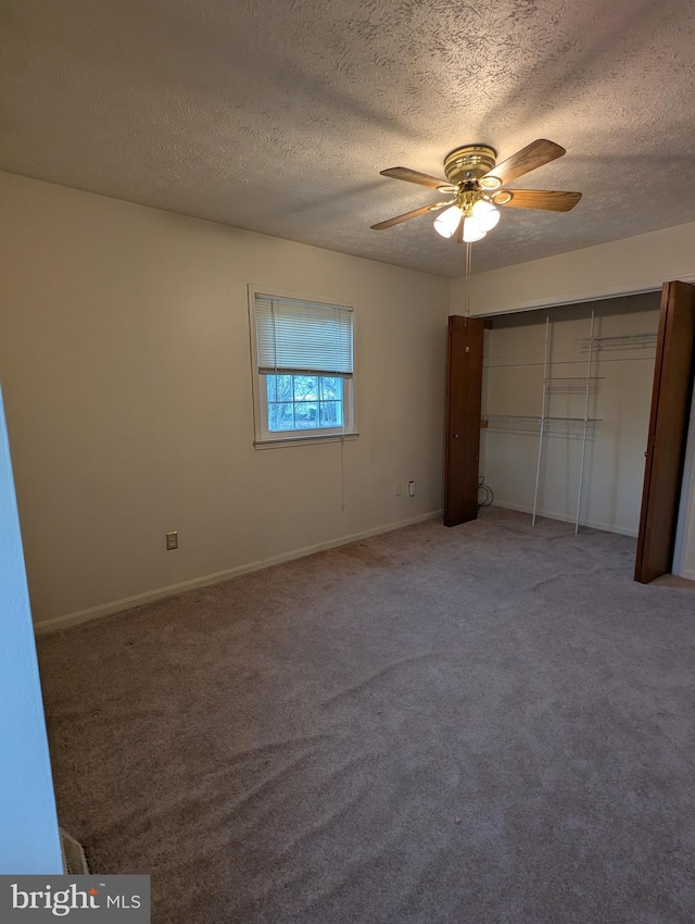 unfurnished bedroom with carpet flooring, a textured ceiling, ceiling fan, and a closet