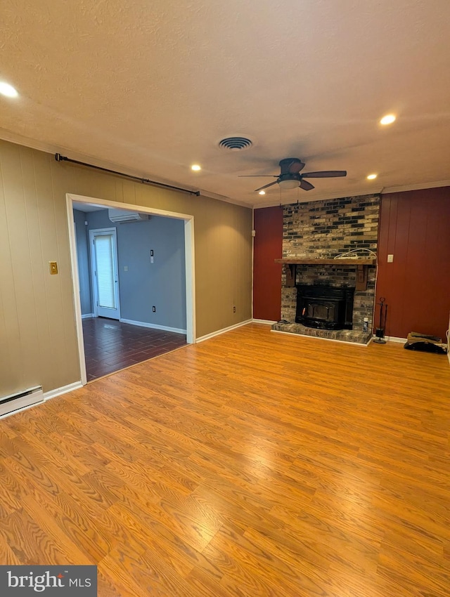 unfurnished living room with ceiling fan, a brick fireplace, light hardwood / wood-style flooring, and a textured ceiling