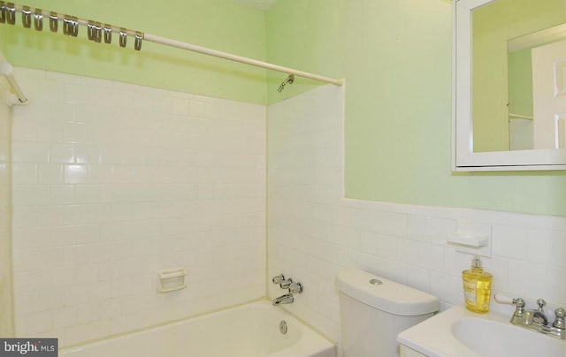 full bathroom featuring vanity, toilet, tiled shower / bath, and tile walls