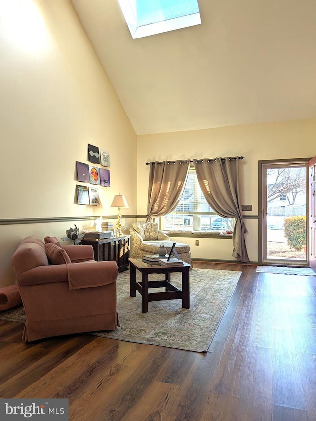 living room featuring hardwood / wood-style flooring, high vaulted ceiling, and a skylight