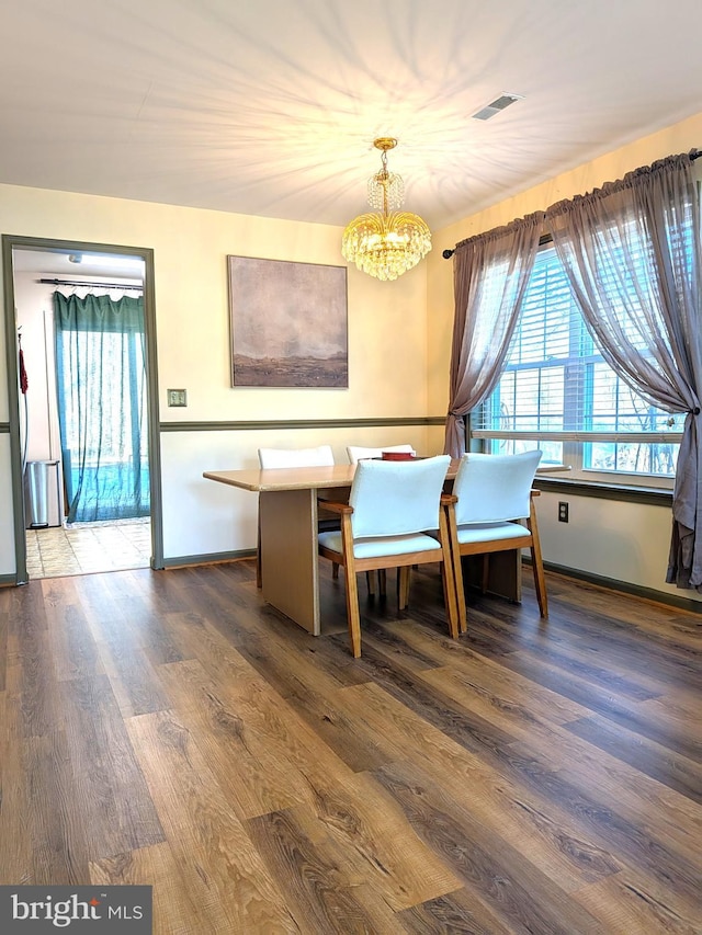 dining space featuring dark hardwood / wood-style flooring and an inviting chandelier