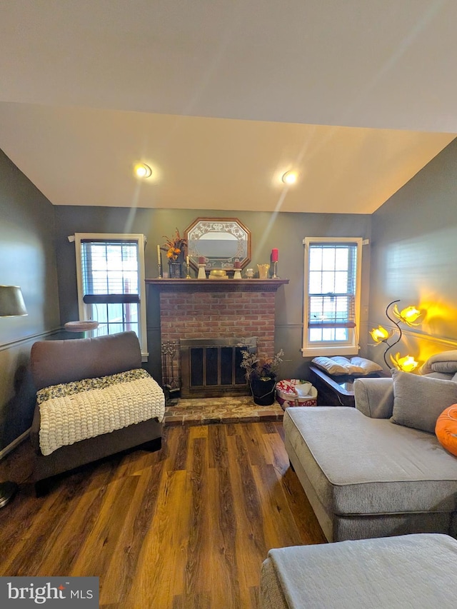 living room featuring dark hardwood / wood-style floors and a brick fireplace