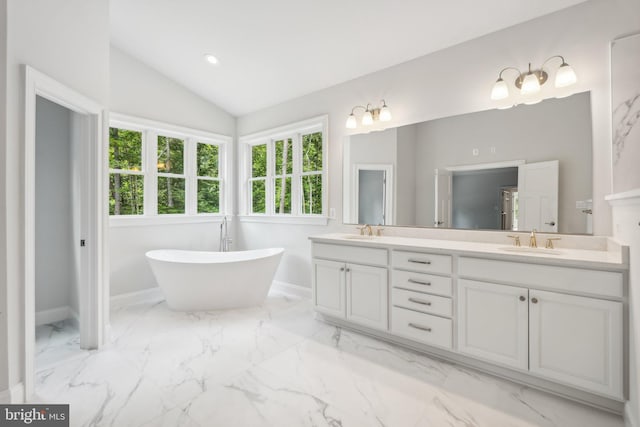 bathroom featuring vanity, a bathing tub, and vaulted ceiling