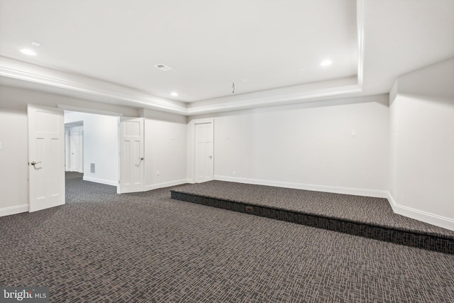 unfurnished room with a tray ceiling and dark colored carpet