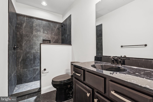 bathroom with tiled shower, toilet, and vanity