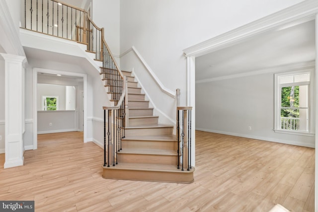 staircase featuring hardwood / wood-style flooring, a healthy amount of sunlight, and ornate columns