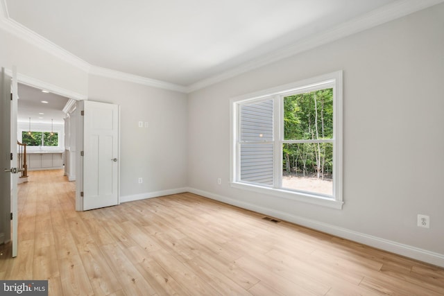 unfurnished room featuring crown molding, light wood-type flooring, and a wealth of natural light