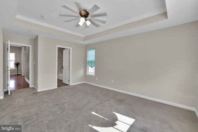 unfurnished bedroom with ceiling fan, a tray ceiling, and ensuite bath