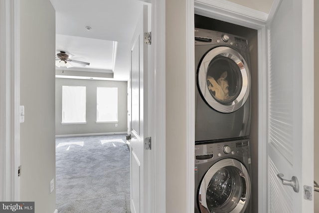 laundry area featuring light carpet, ceiling fan, and stacked washer / drying machine