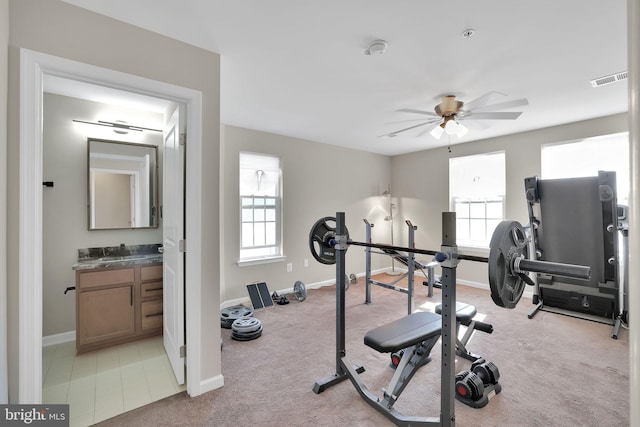 exercise area featuring light colored carpet and ceiling fan