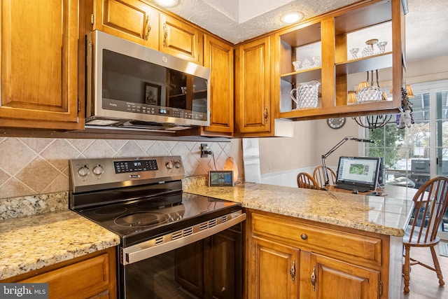 kitchen with light stone counters, backsplash, and stainless steel appliances