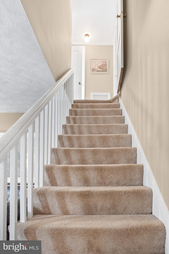 staircase featuring a textured ceiling