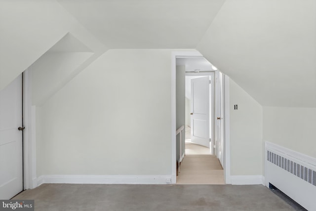 additional living space featuring vaulted ceiling, radiator, and light carpet