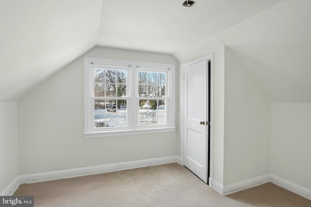 additional living space featuring light colored carpet and vaulted ceiling