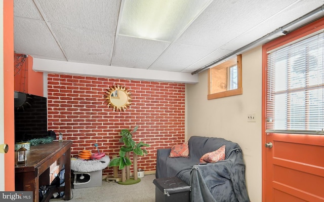 sitting room featuring brick wall and a drop ceiling