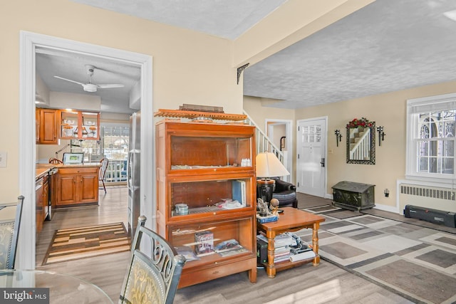 interior space featuring ceiling fan, radiator, light hardwood / wood-style floors, and a textured ceiling