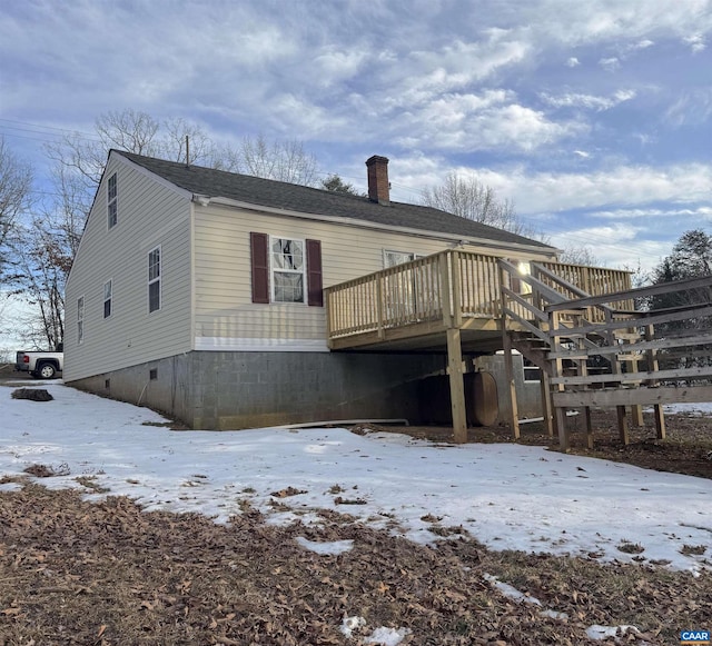 snow covered rear of property with a wooden deck