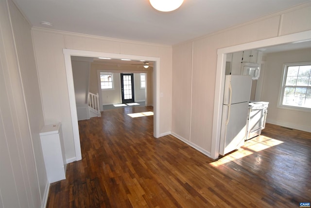 corridor featuring a healthy amount of sunlight, crown molding, and dark hardwood / wood-style flooring