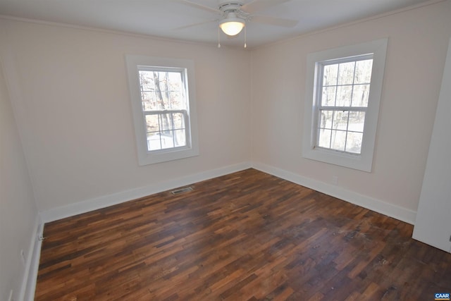 spare room with a wealth of natural light, crown molding, and dark hardwood / wood-style floors