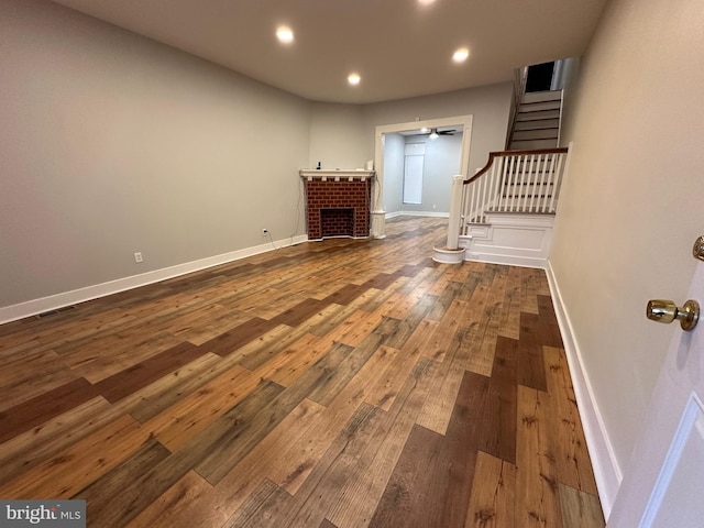 unfurnished living room featuring a brick fireplace and dark hardwood / wood-style floors